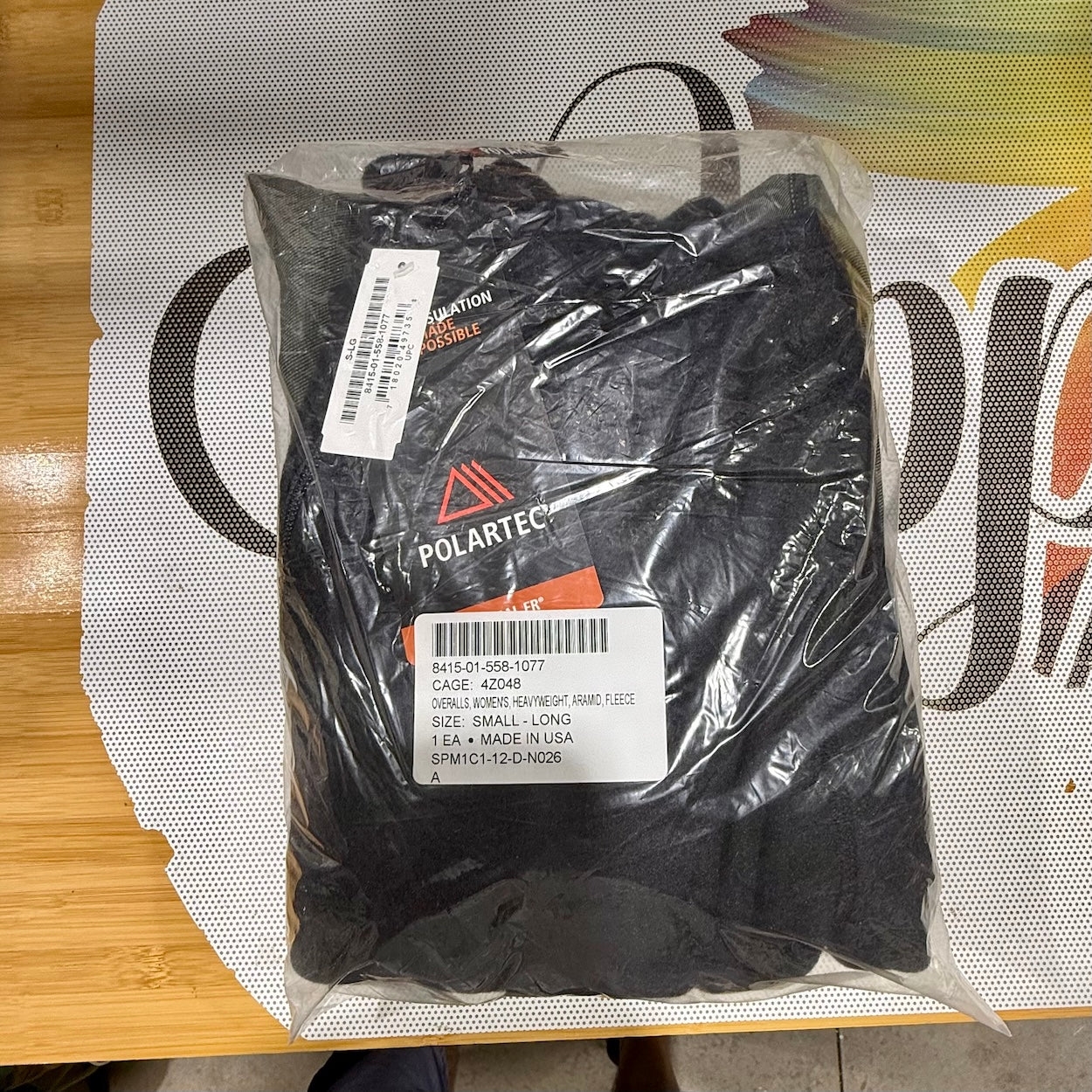 Packaged black gloves with Polartec branding on a colorful background